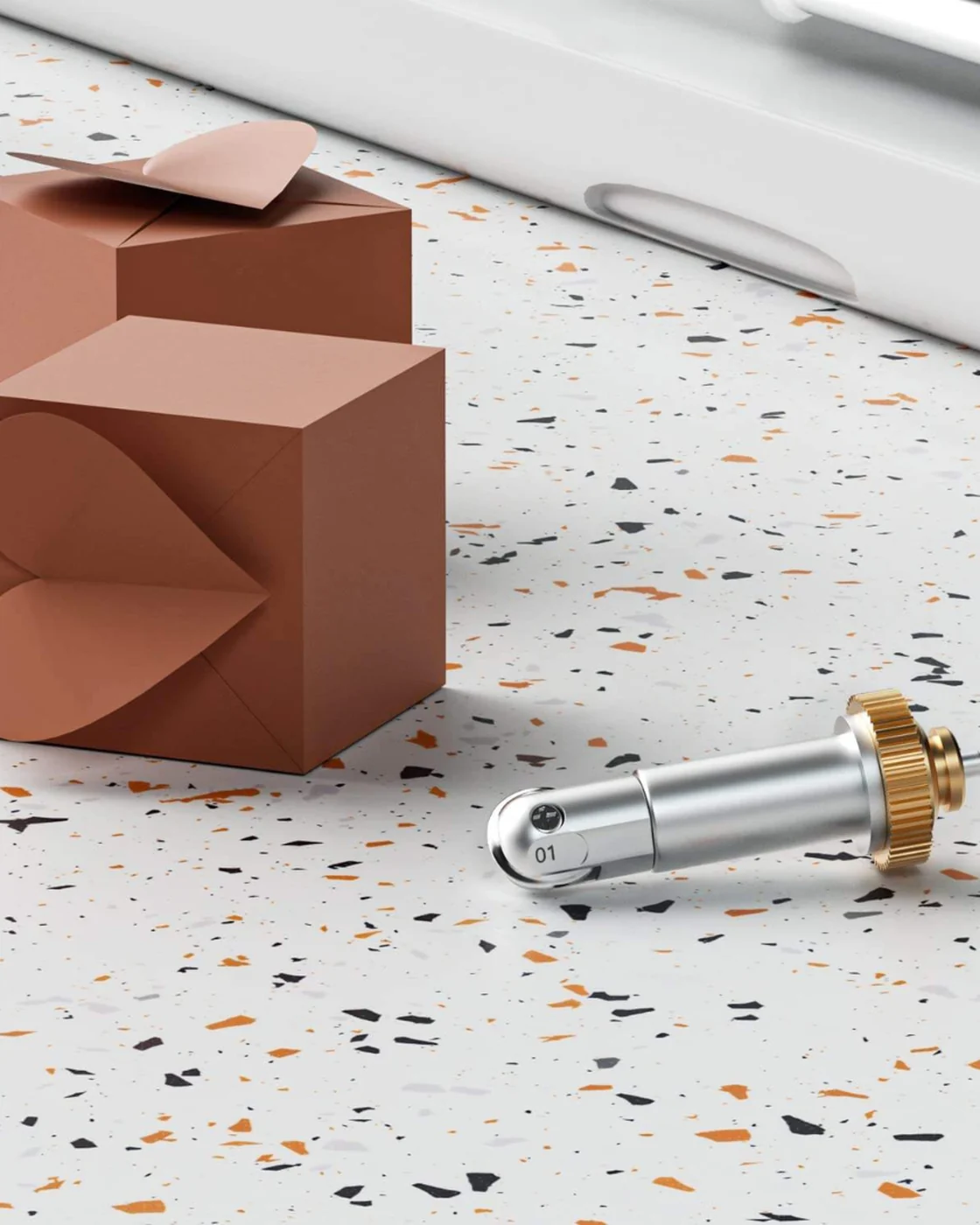 Deux boîtes cadeaux en papier pliées et rainées, posées près de l’outil de rainage Wellkitch sur un plan de travail.